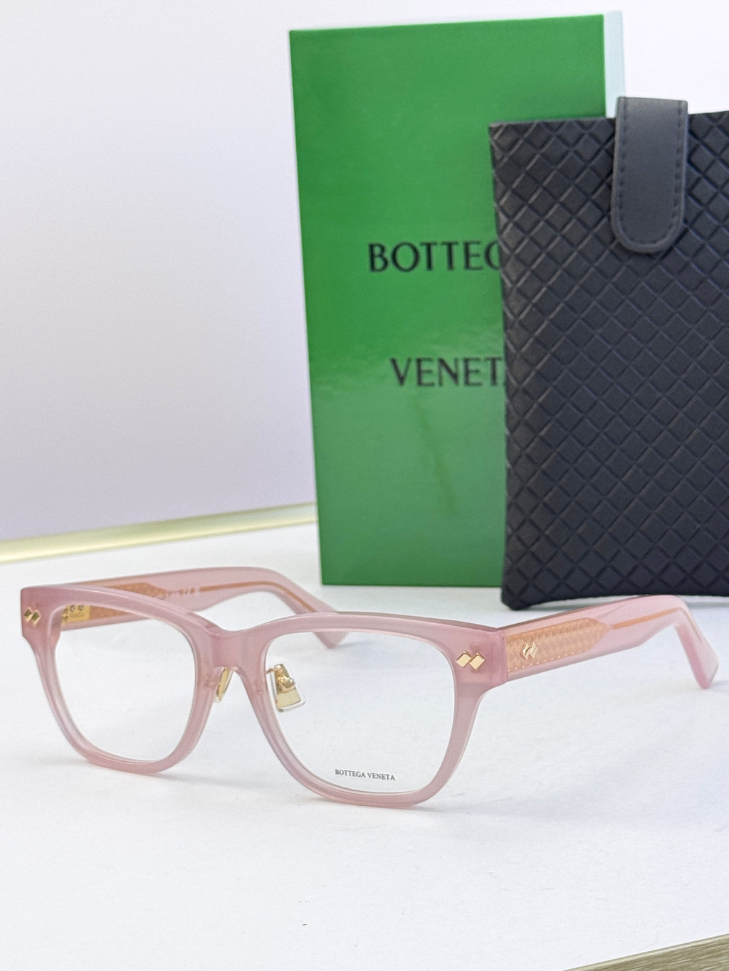 Pink eyeglasses with gold temple accents and rectangular clear lenses.