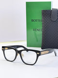 Black eyeglasses with gold temple accents and rectangular clear lenses.
