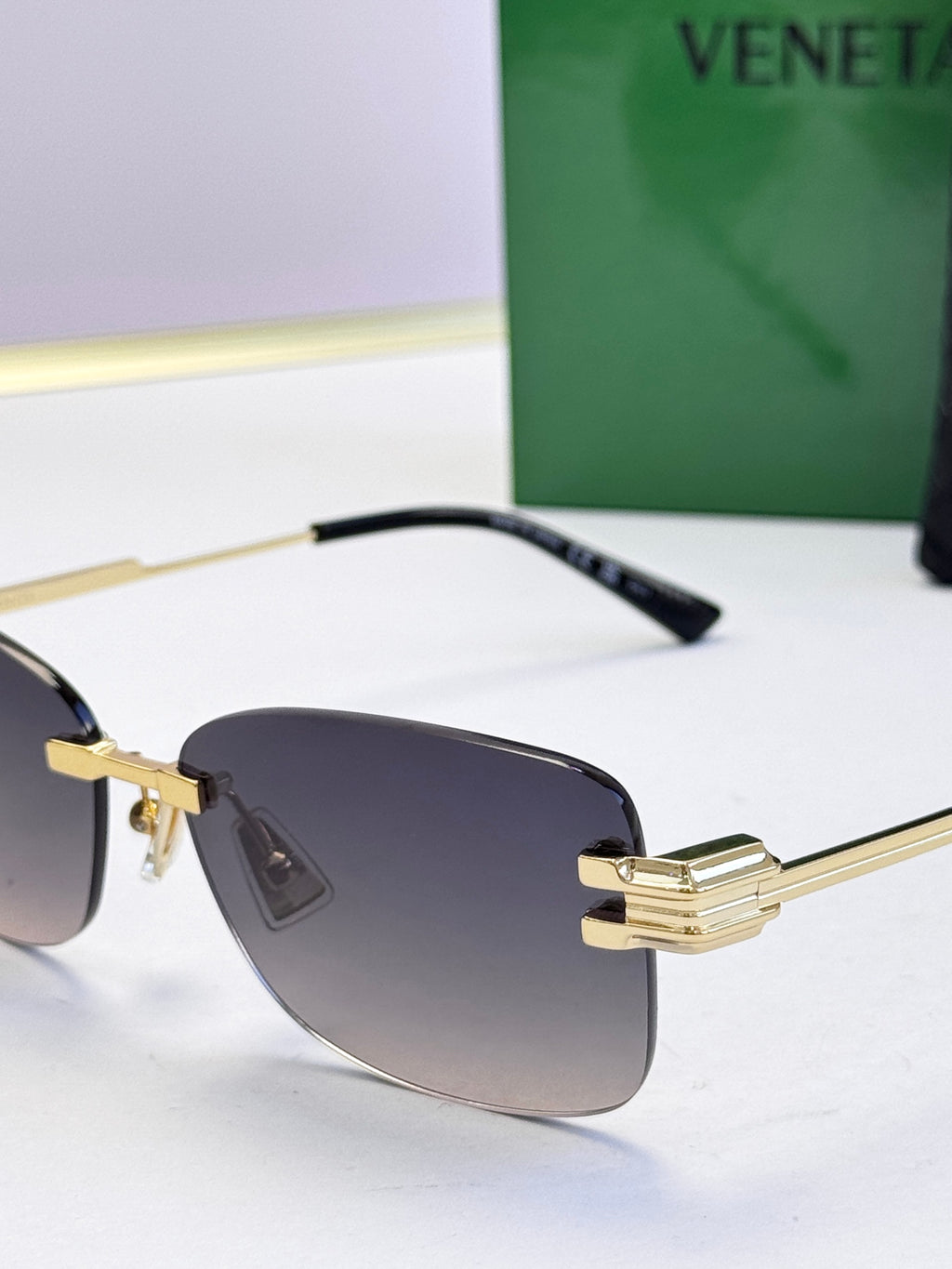 Bottega Veneta sunglasses close-up with gold frame, black temple, dark lenses