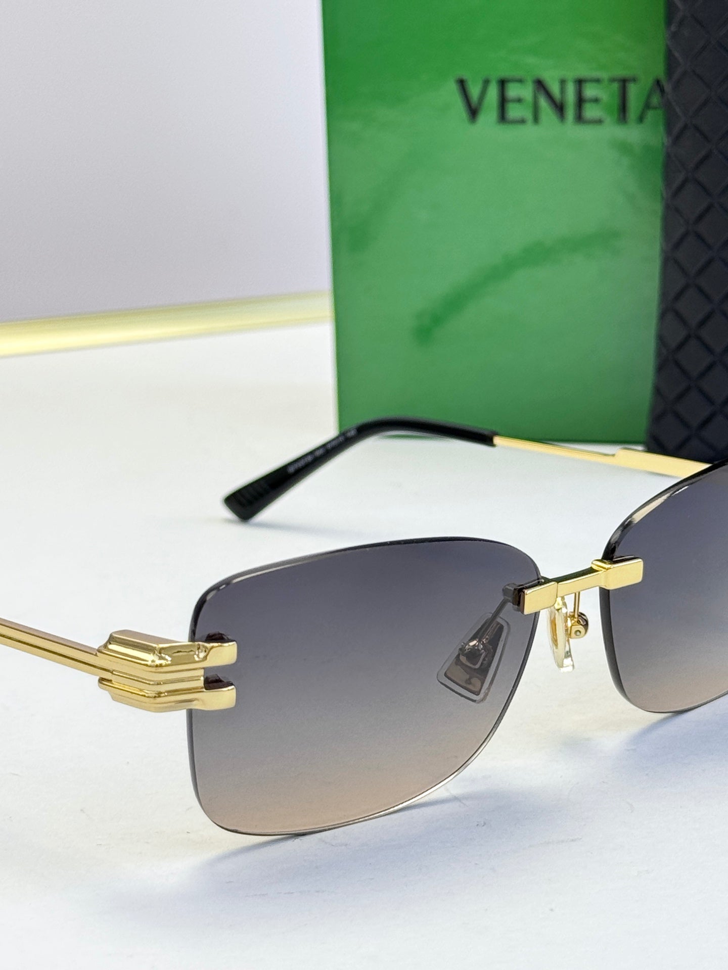 Bottega Veneta sunglasses close-up with gold frame and dark gradient lenses