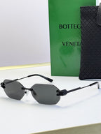 Bottega Veneta sunglasses with black frame and light gray tinted lenses, octagonal shape.