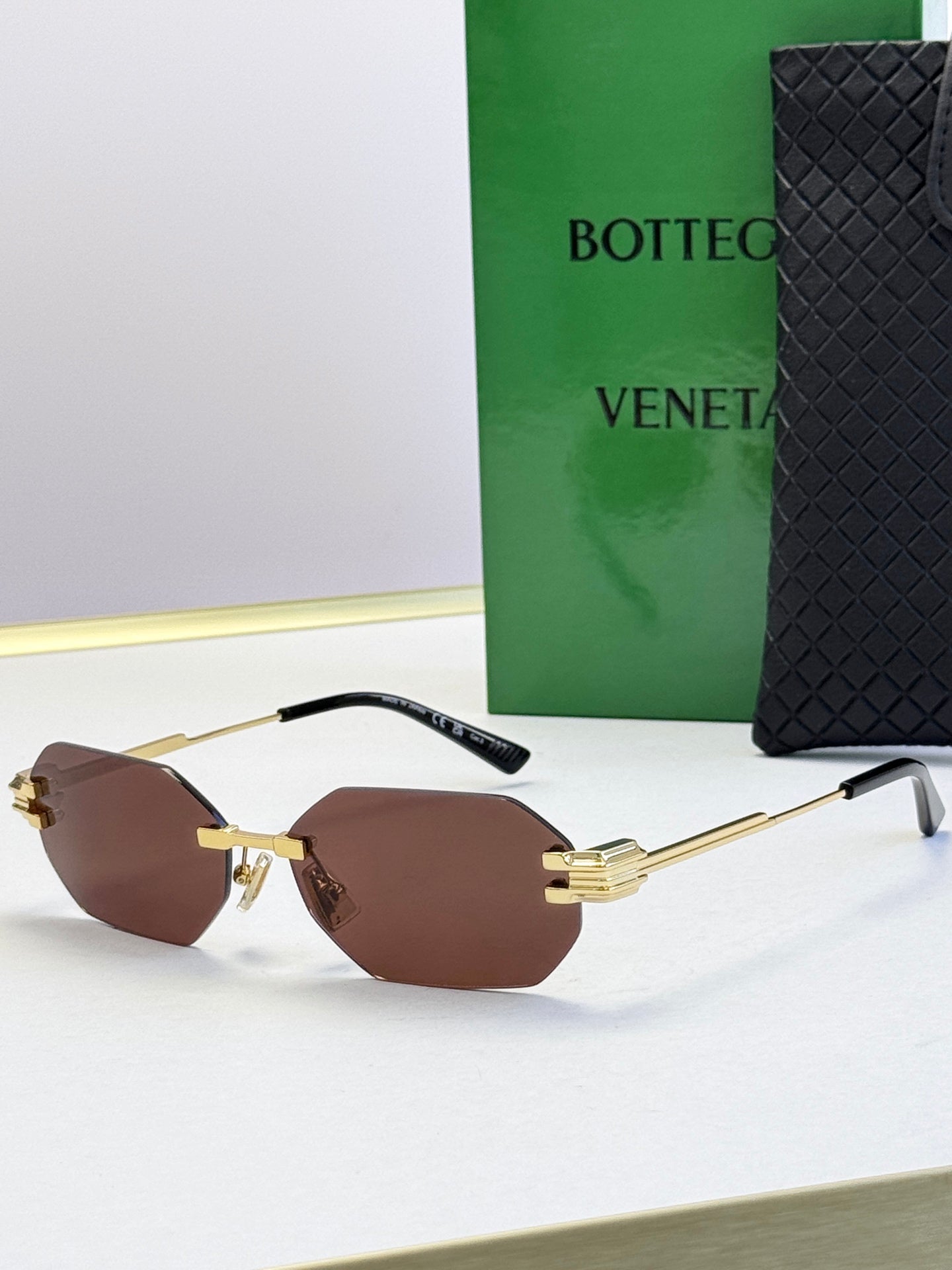 Bottega Veneta sunglasses with gold frame and brown tinted lenses, octagonal shape.