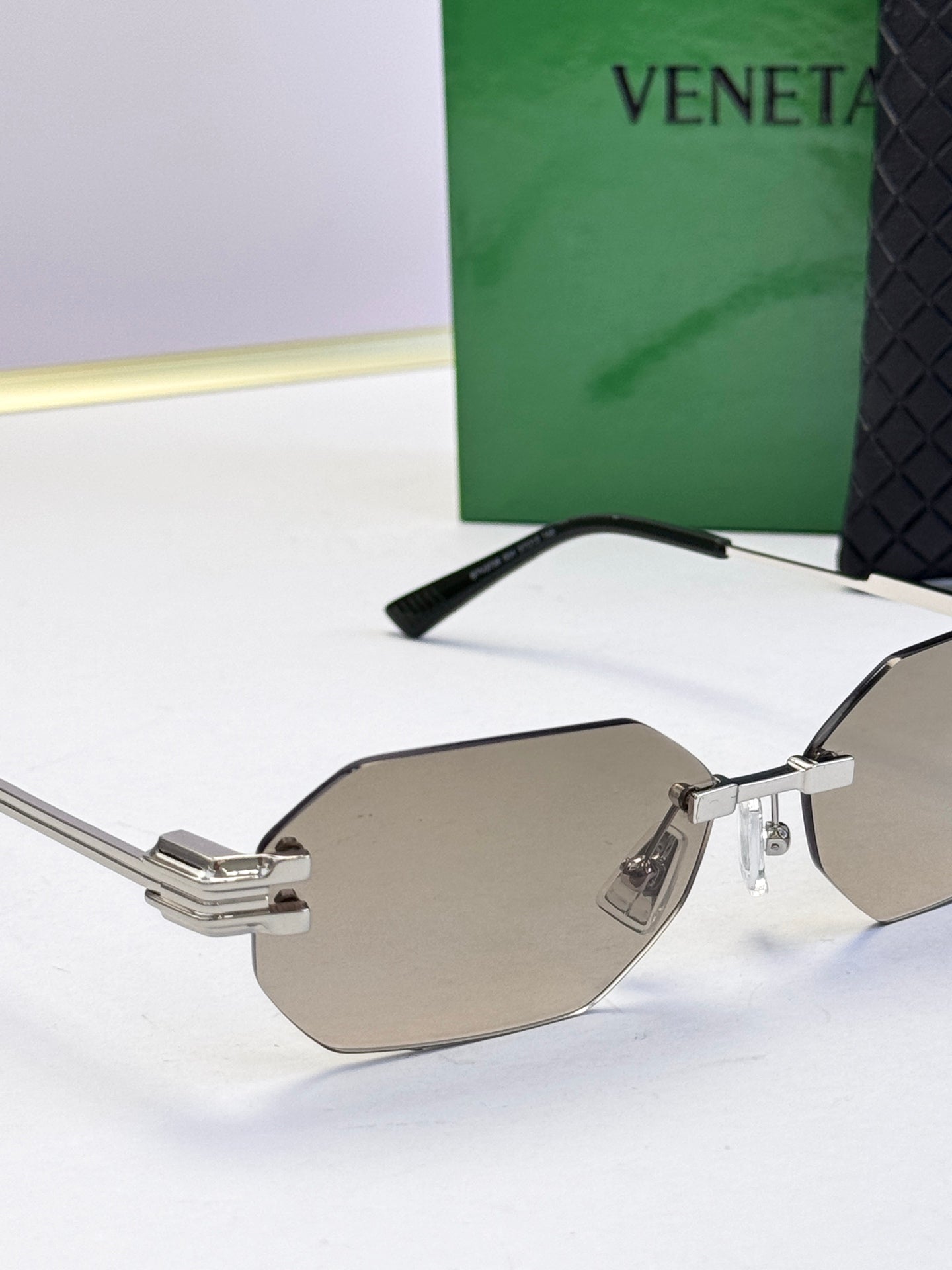 Bottega Veneta sunglasses close-up with silver frame and taupe tinted lenses, octagonal.