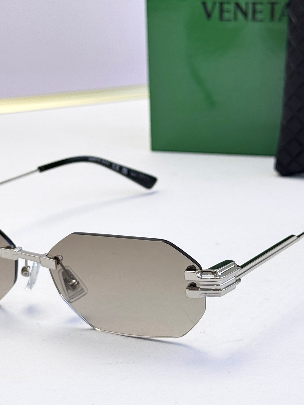 Bottega Veneta sunglasses close-up with silver frame and taupe tinted lenses, octagonal.