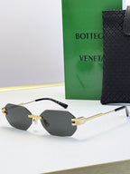 Bottega Veneta sunglasses with gold frame and light gray tinted lenses, octagonal shape.