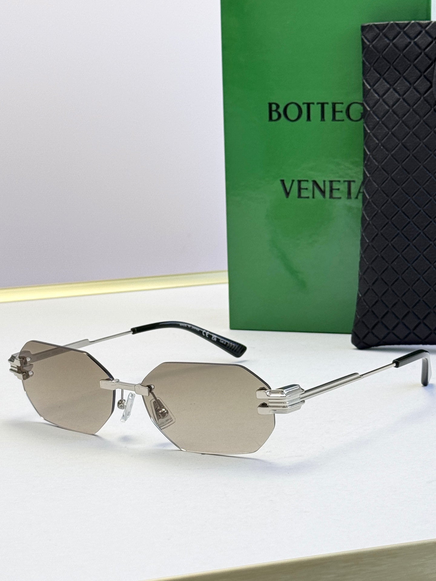Bottega Veneta sunglasses with light metal frame and taupe tinted lenses, octagonal shape.