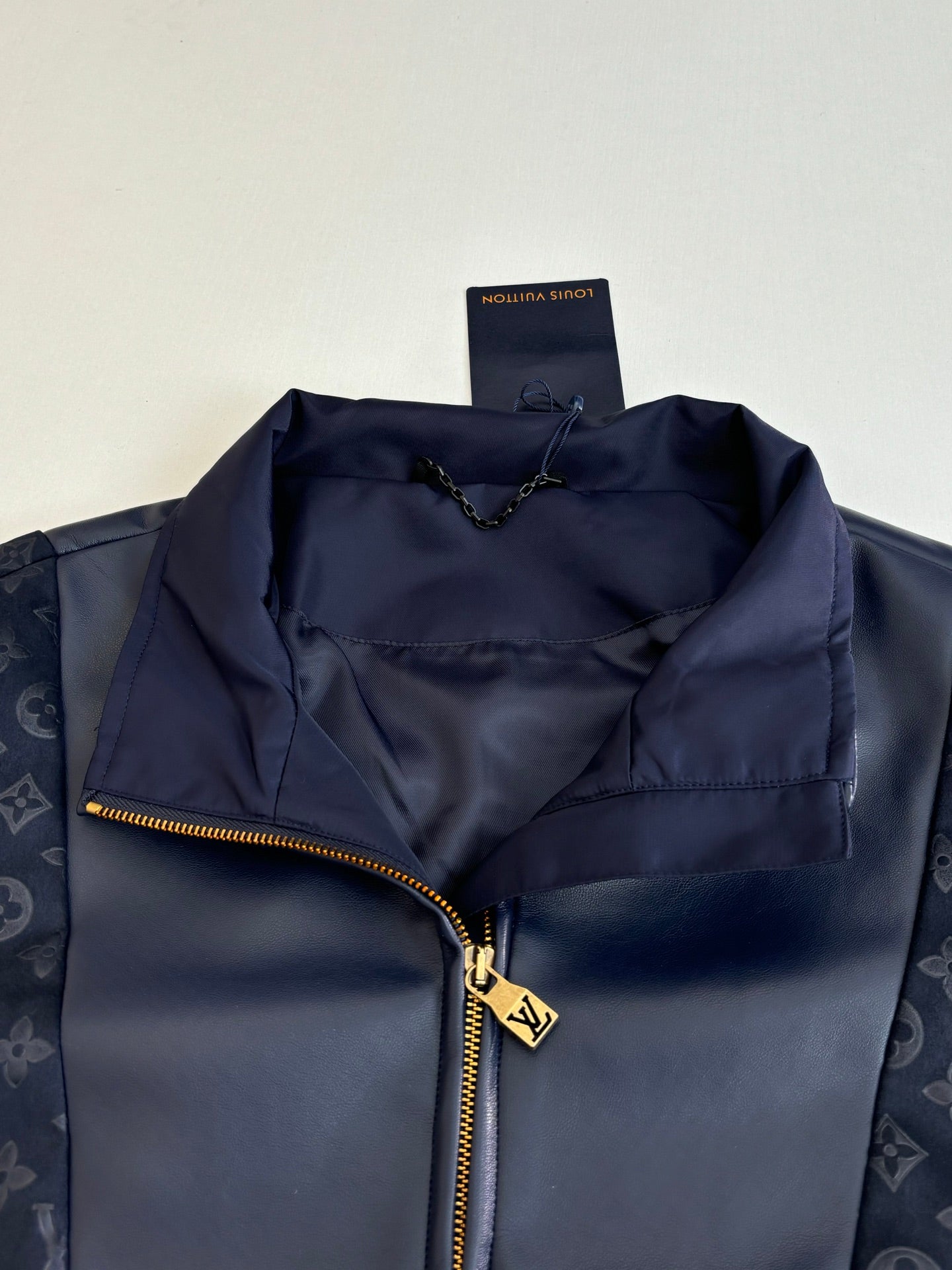 Navy jacket close-up with gold-tone zipper and interior lining pocket