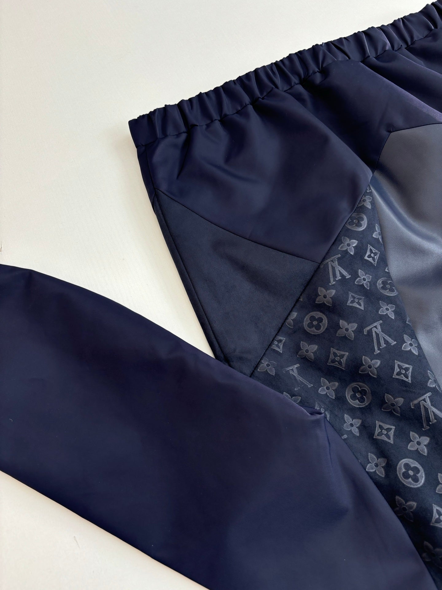 Navy pants close-up with elastic waistband and subtle monogram fabric panel