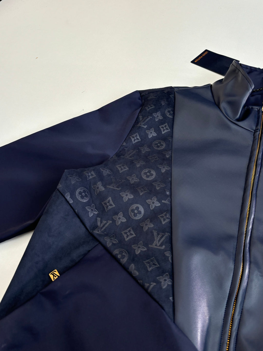 Navy jacket sleeve and zipper close-up with LV-style monogram patch