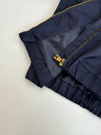 Navy ruffled cuff pants close-up with gold zipper and small LV-style emblem