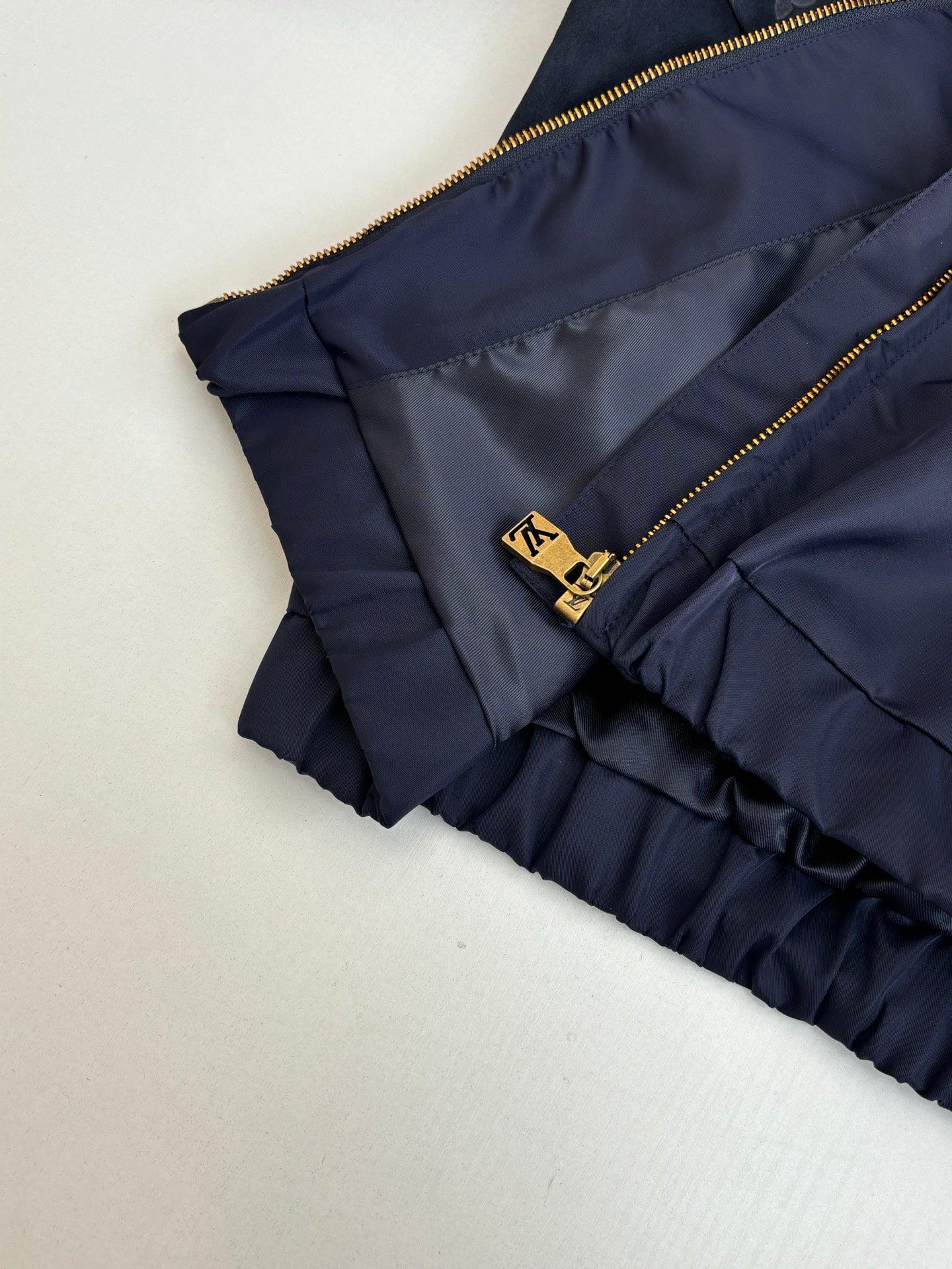 Navy ruffled cuff pants close-up with gold zipper and small LV-style emblem