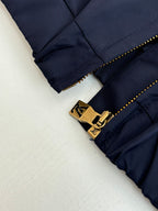 Navy pants leg close-up with gold zipper pull and LV-style belt logo hardware