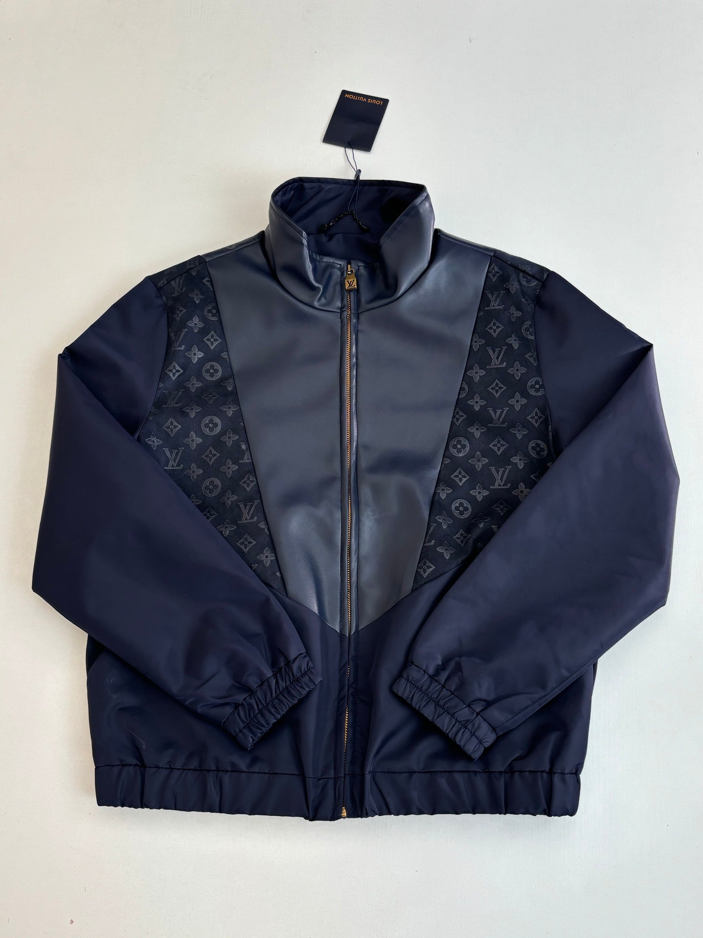 Navy zip-up jacket with stand collar; monogram side panels and ribbed hem