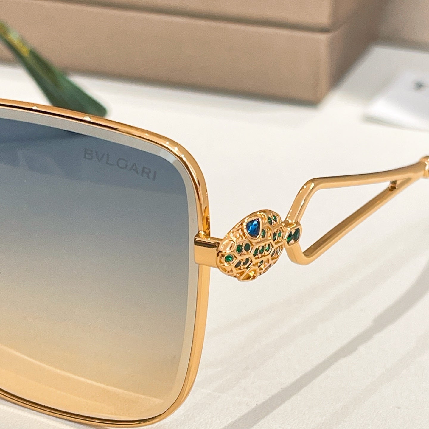 Bvlgari sunglasses close-up: gold frame with jeweled hinge and blue lens
