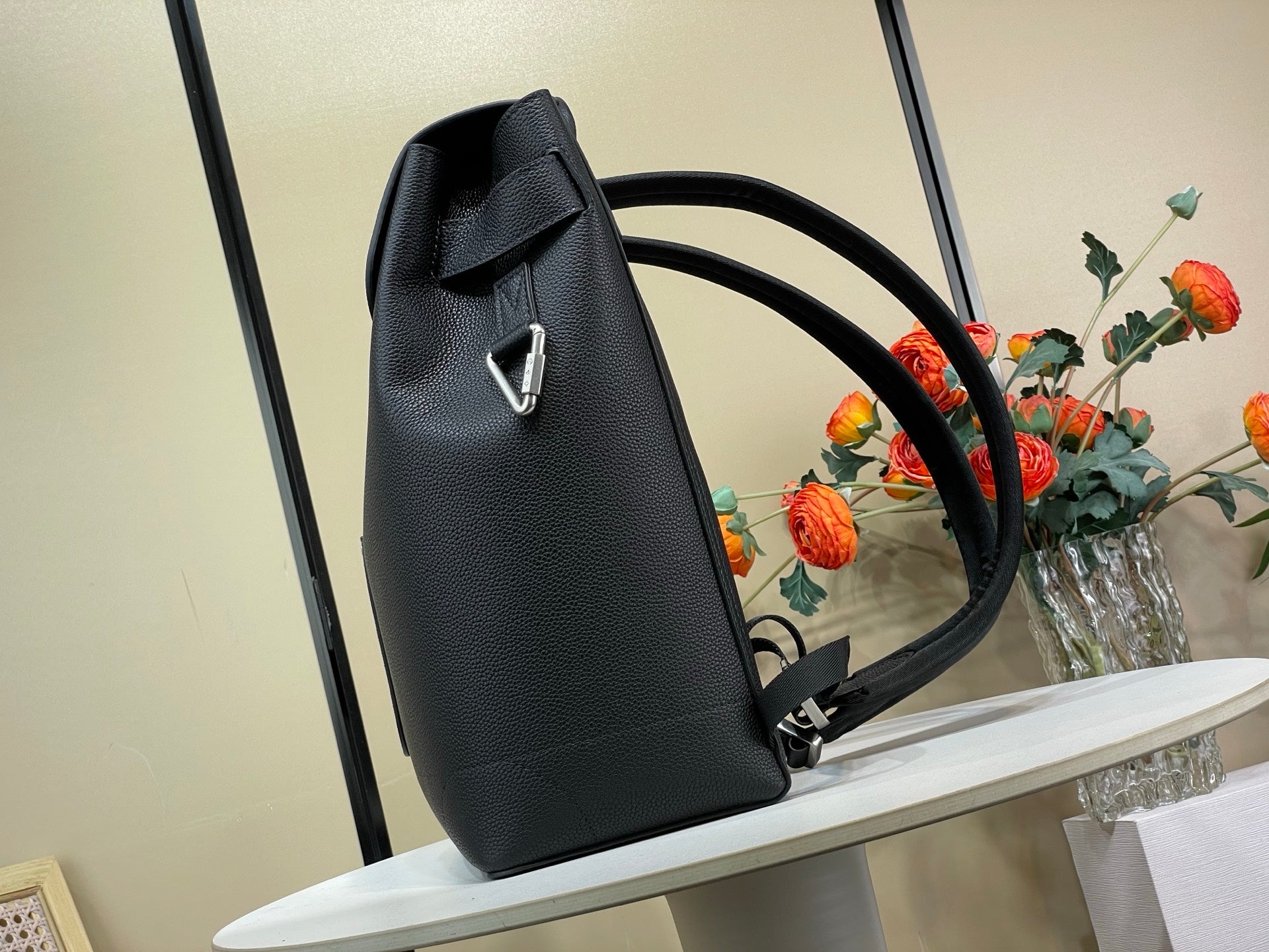 Louis Vuitton bag angled view, dark leather with top handle and long shoulder strap