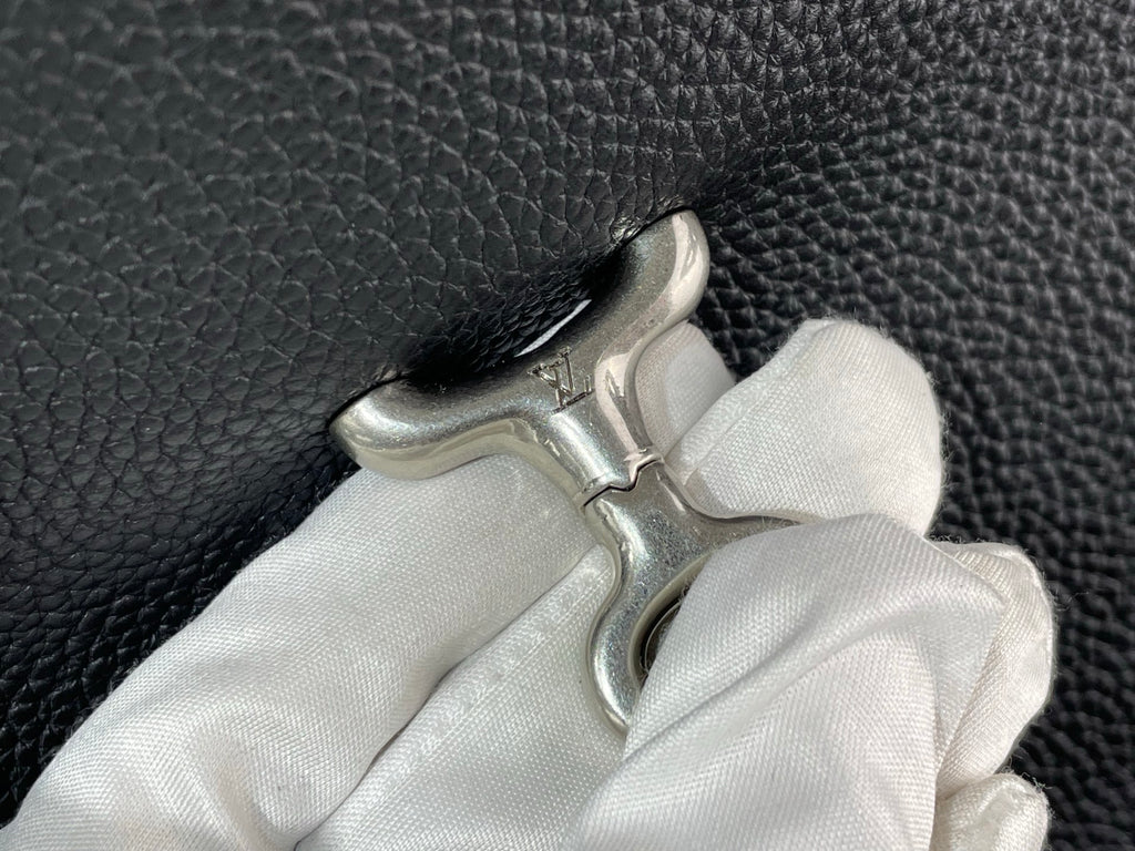 Pebbled leather bag handle with metal clasp and white cloth, close-up
