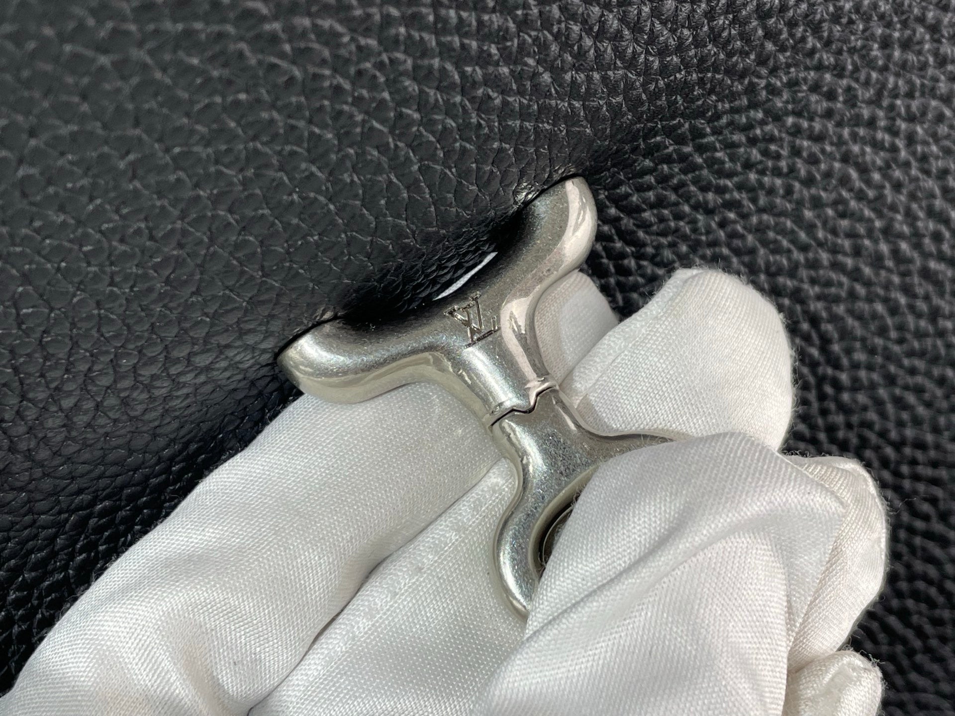 Pebbled leather bag handle with metal clasp and white cloth, close-up