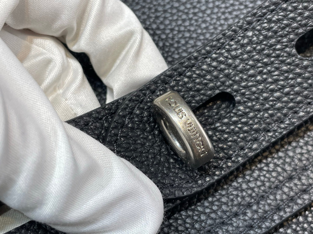 Louis Vuitton bag close-up of engraved metal buckle with logo on leather strap