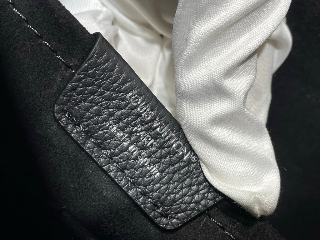 Black pebbled leather bag pocket with zipper edge and white cloth, close-up