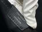 Black pebbled leather bag pocket with zipper edge and white cloth, close-up
