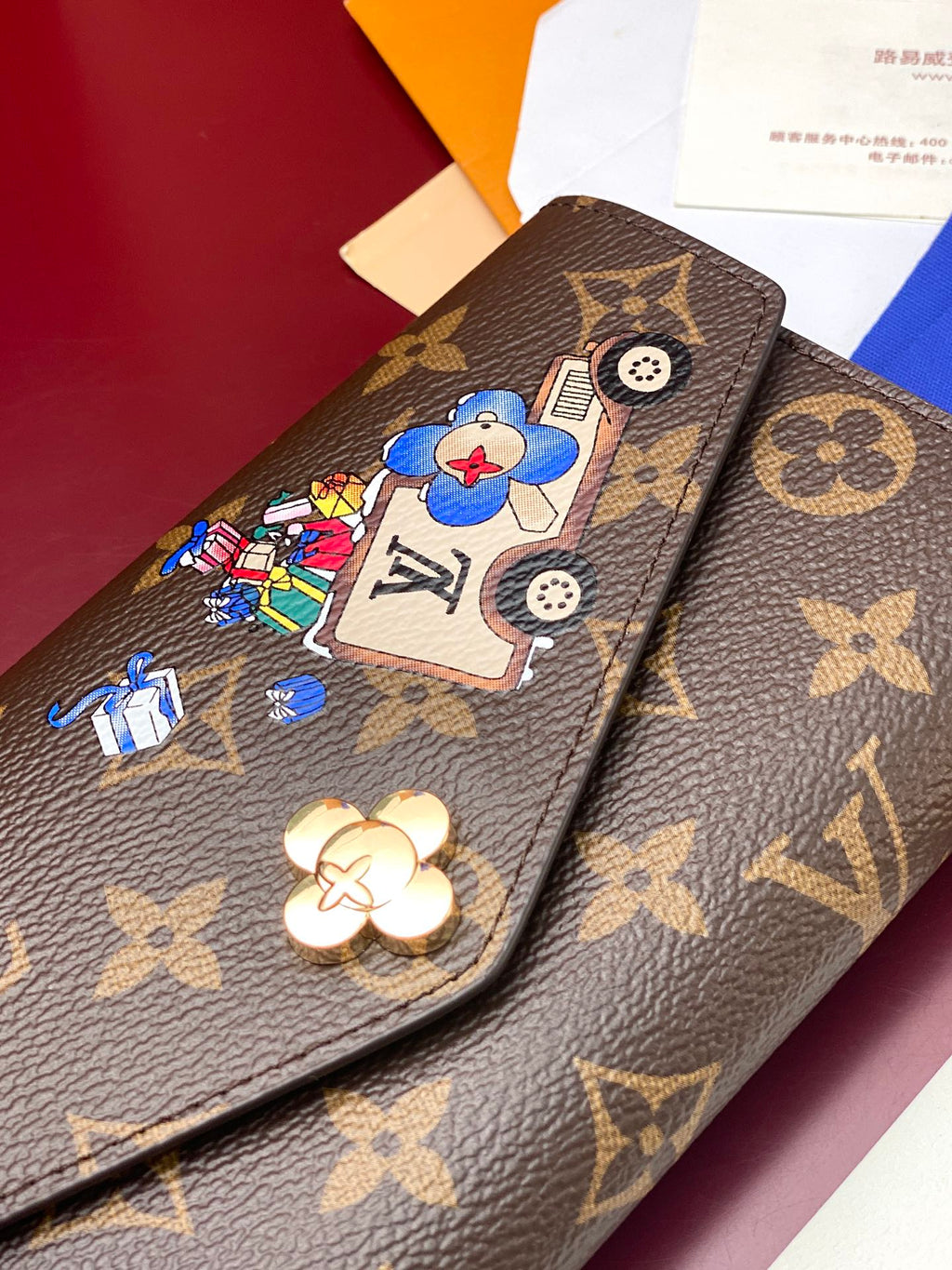 Louis Vuitton small bag close-up with brown monogram, blue cartoon patch, and button detail.