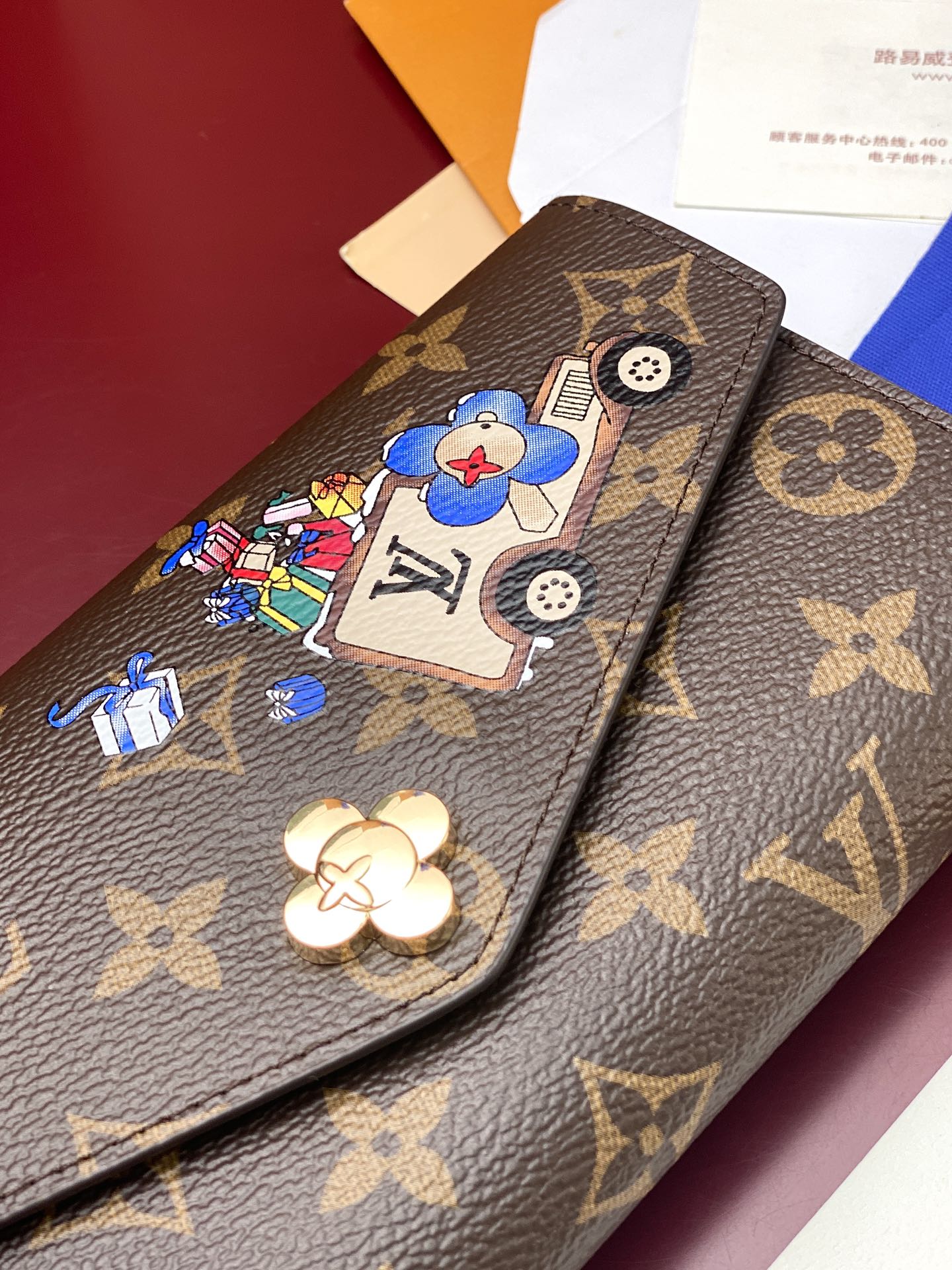 Louis Vuitton small bag close-up with brown monogram, blue cartoon patch, and button detail.