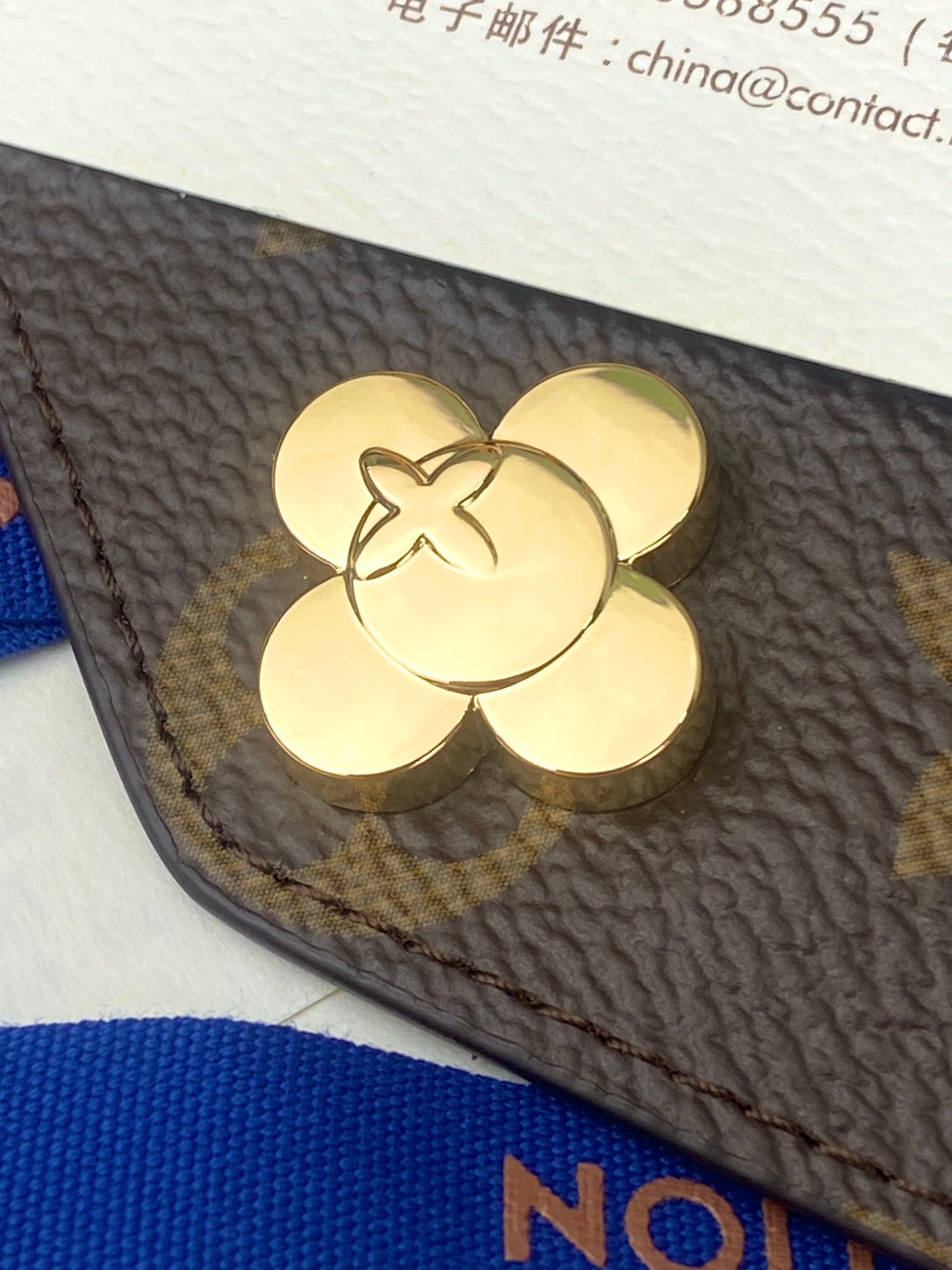 Dark textured bag flap with gold four-petal clasp detail