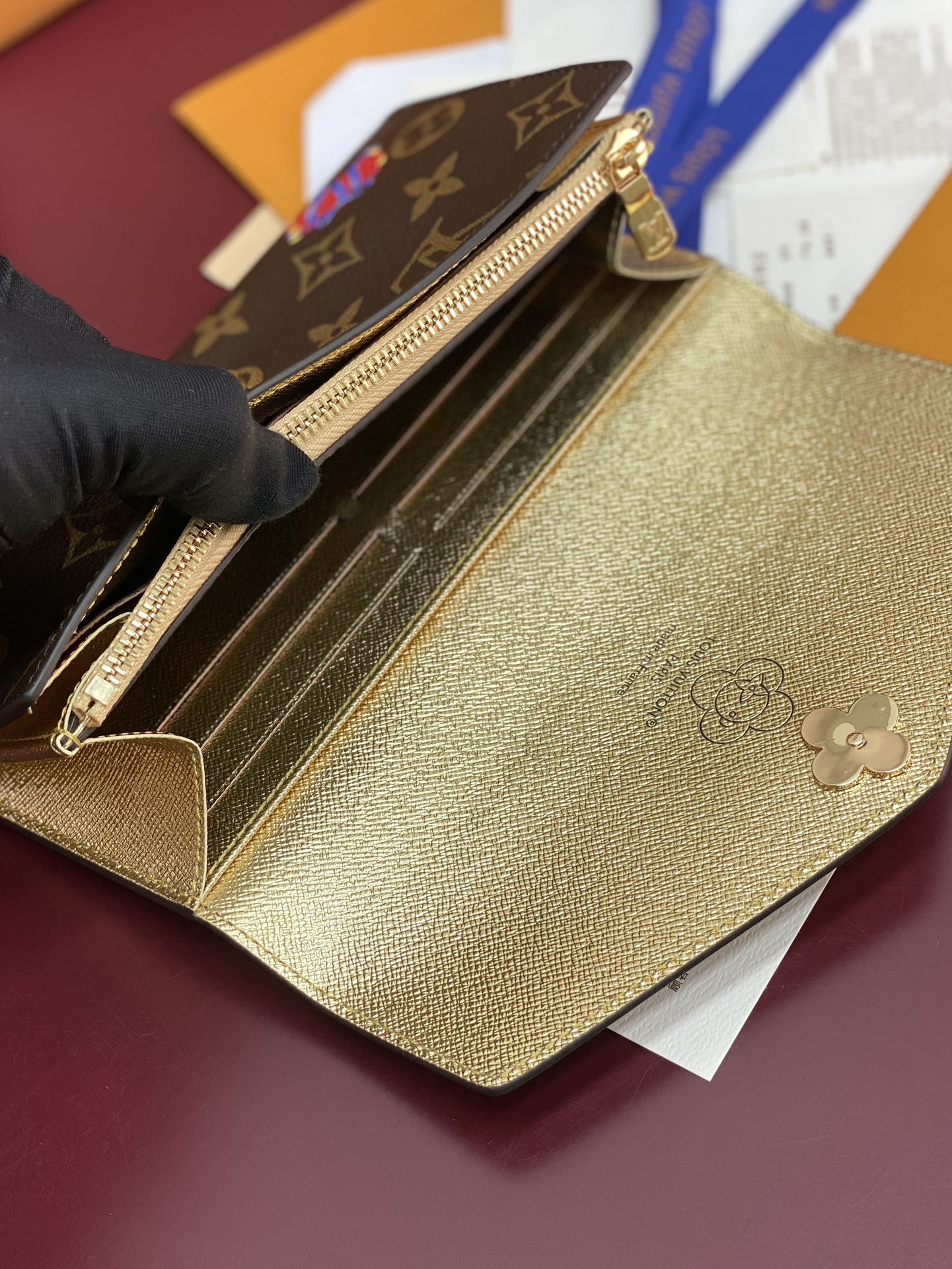 Louis Vuitton small bag open to show gold interior with structured card slots and zipper.