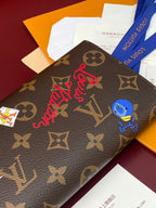 Louis Vuitton small bag close-up with brown monogram, red script logo, and blue charm patch.