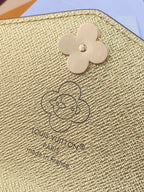 Louis Vuitton small bag close-up: gold textured flap with clover logo and embossed mark.