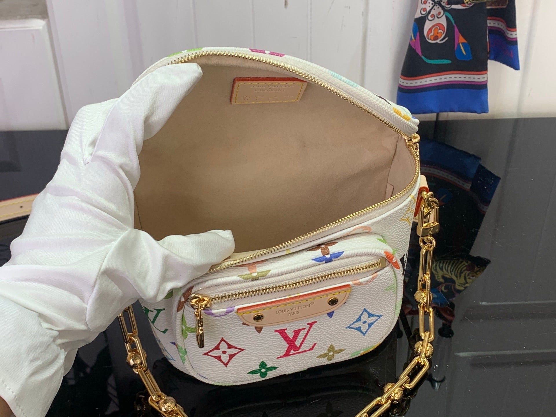 Crossbody bag with open top, white interior lining, gold zipper and front monogram flap