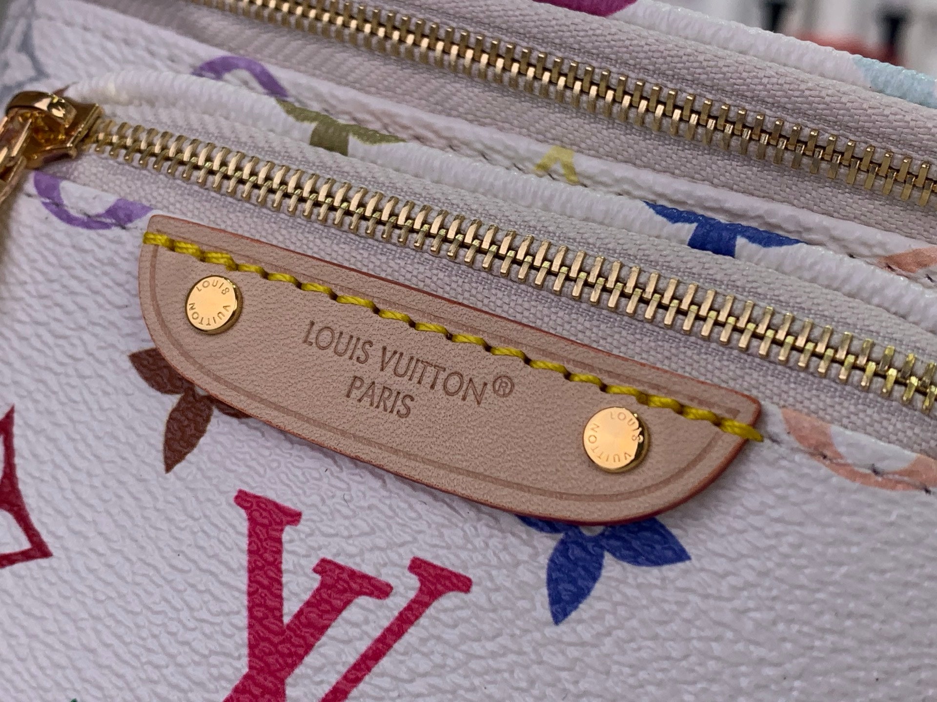 Zip pouch detail on white leather bag, gold zipper and Louis Vuitton logo plaque