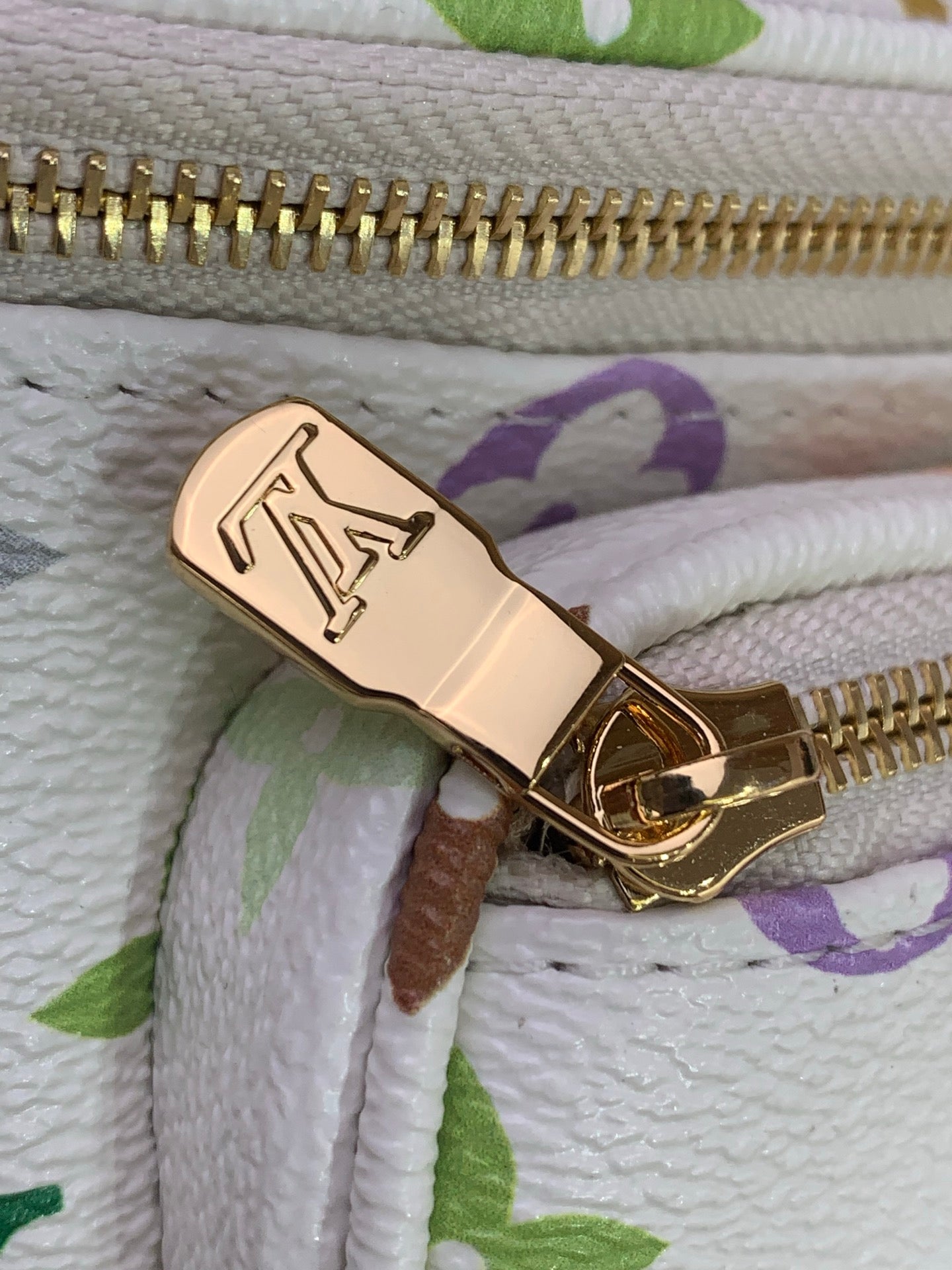 Gold zipper pull and LV monogram tag on white multicolor patterned bag
