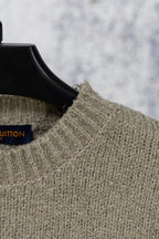 Khaki knit sweater collar with blue Louis Vuitton label on hanger