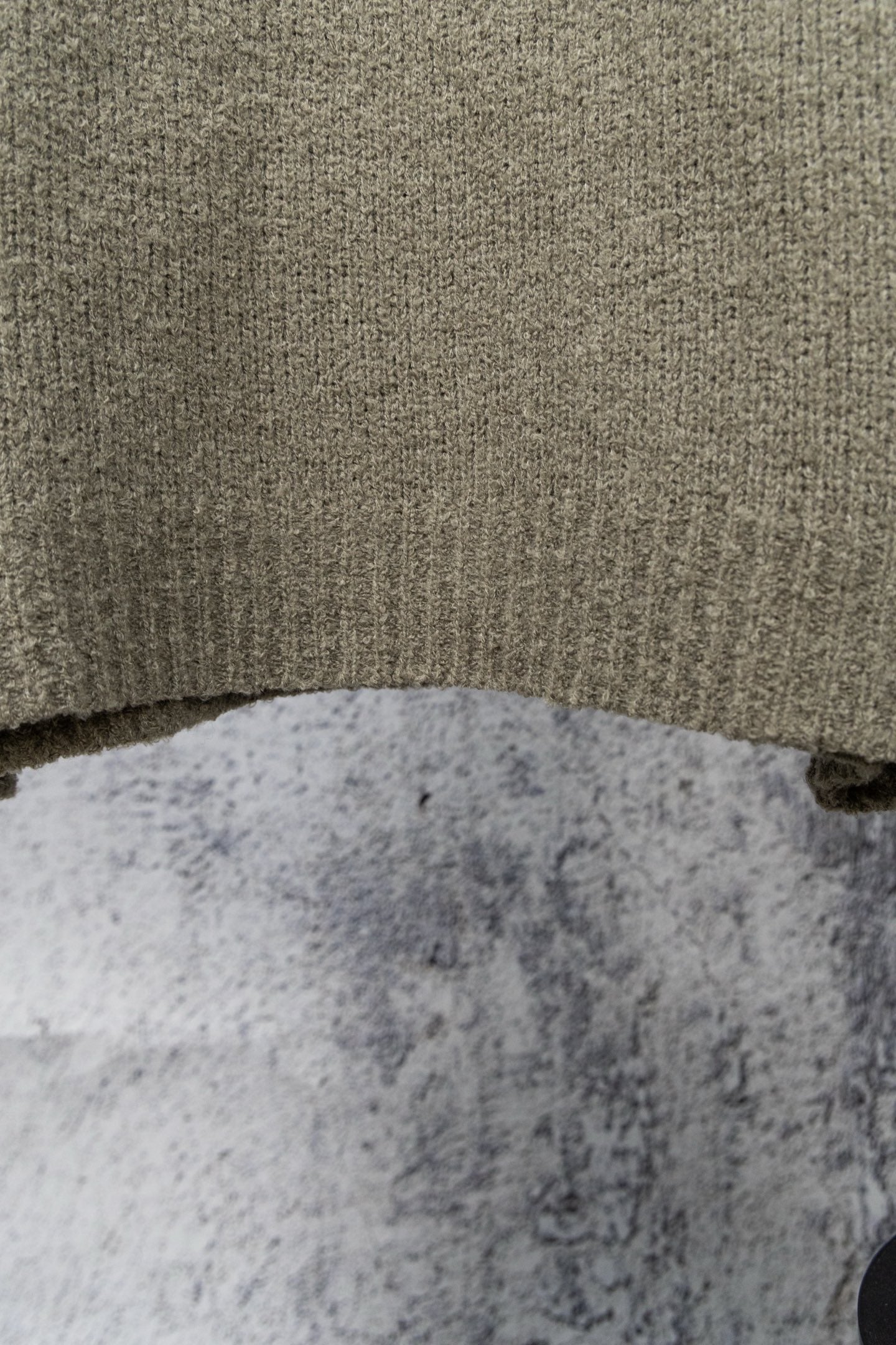 Khaki knit sweater hem and textured fabric close-up