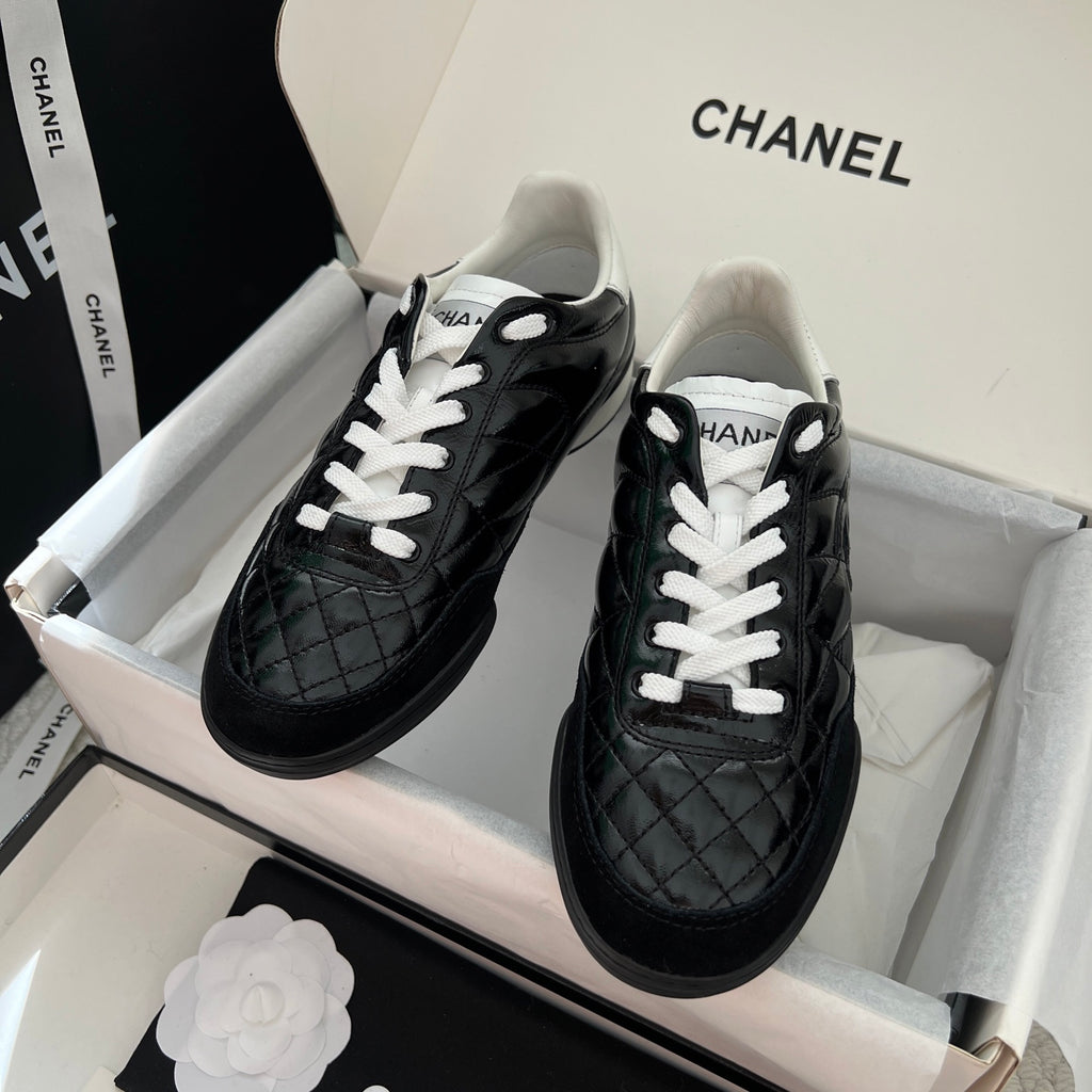 Black quilted unisex sneakers with white laces and thick rubber sole, Chanel logo detail