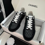 Black quilted unisex sneakers with white laces and thick rubber sole, Chanel logo detail