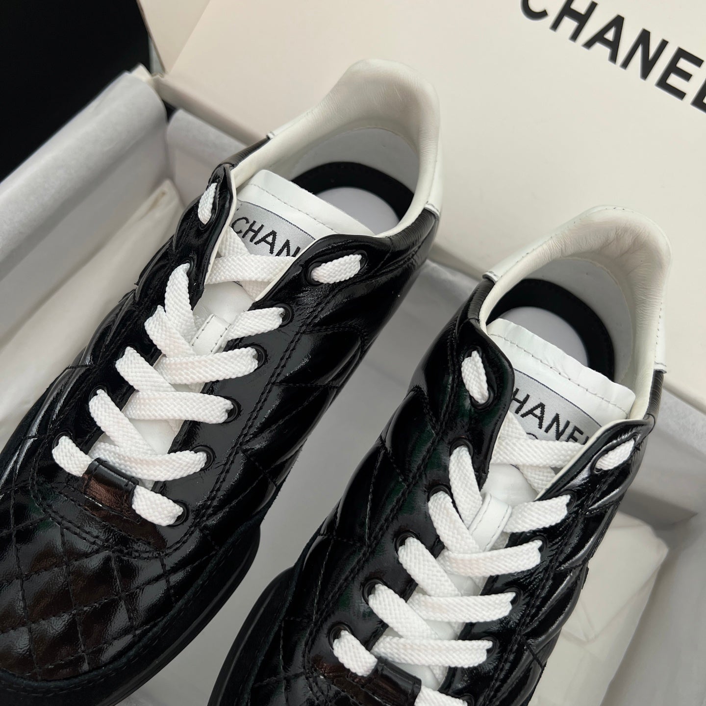 Black and white unisex sneakers with quilted texture and white lace-up front