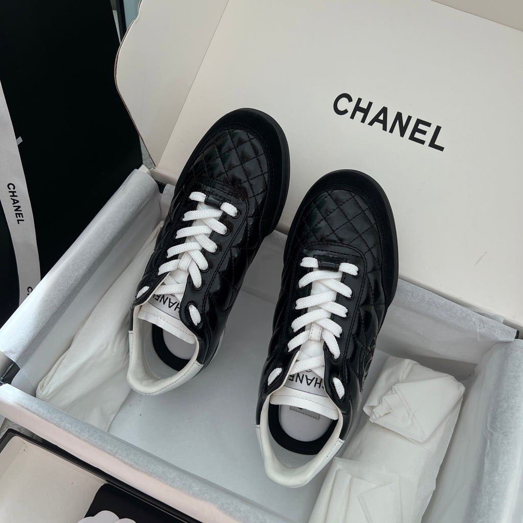 Pair of black unisex quilted sneakers with white laces and contrasting white trim