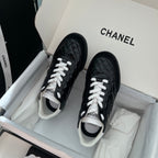 Pair of black unisex quilted sneakers with white laces and contrasting white trim