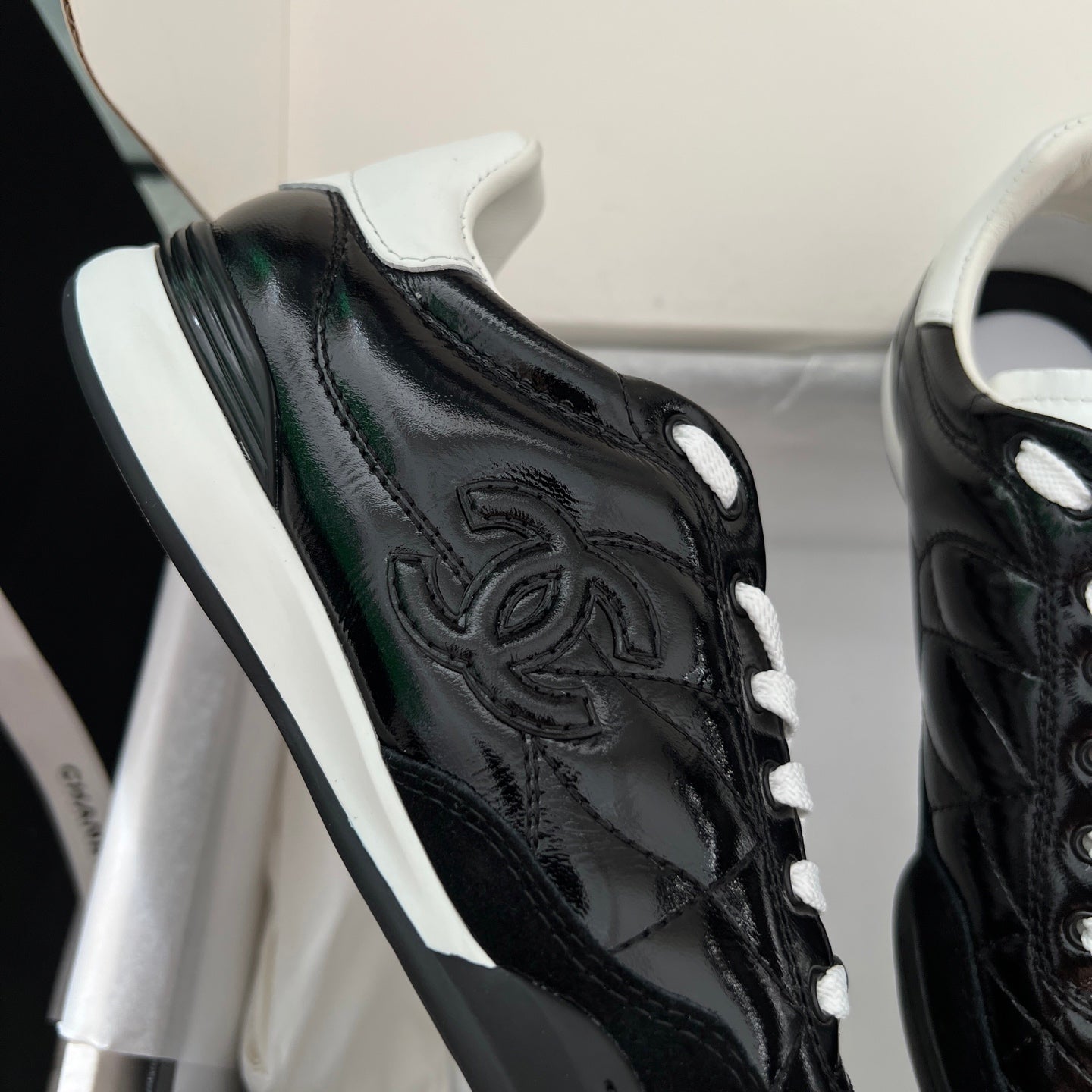 Black quilted unisex sneakers with white lace-up detail and embossed side logo