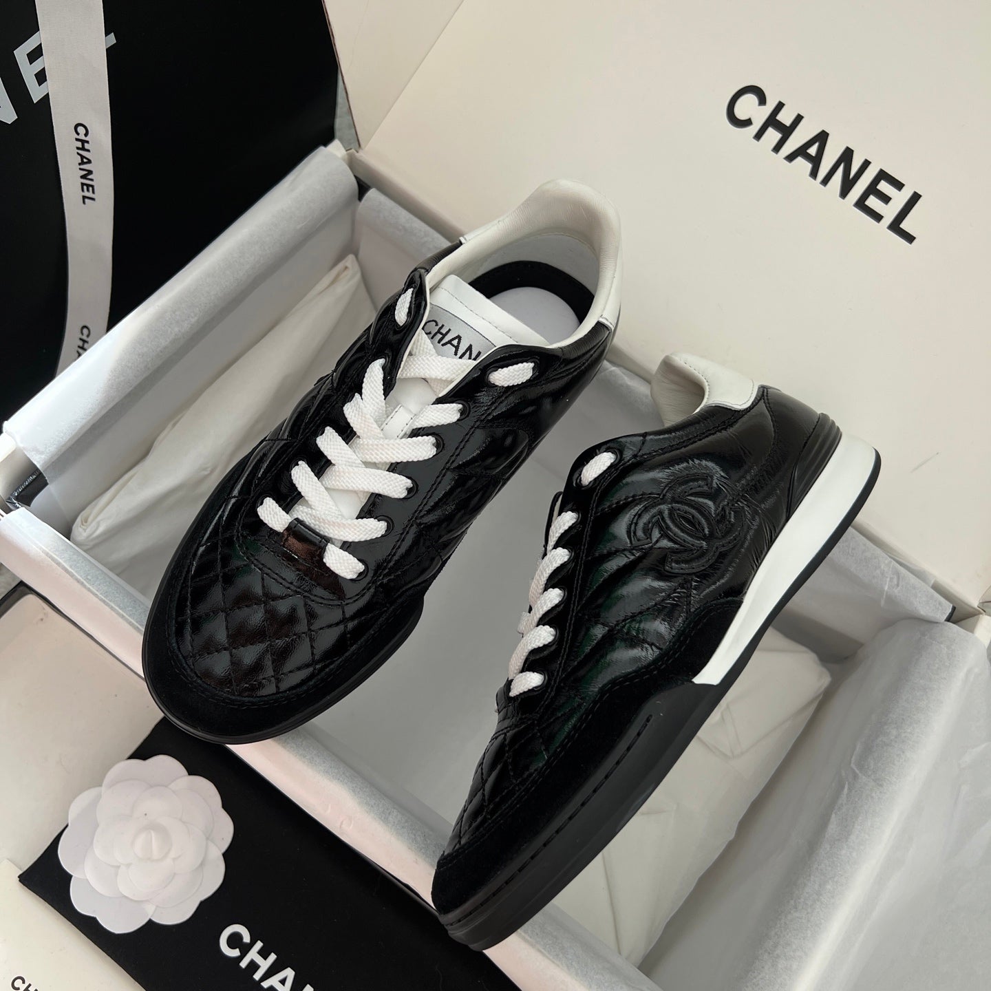Black quilted unisex sneakers with white laces and Chanel-style logo on side