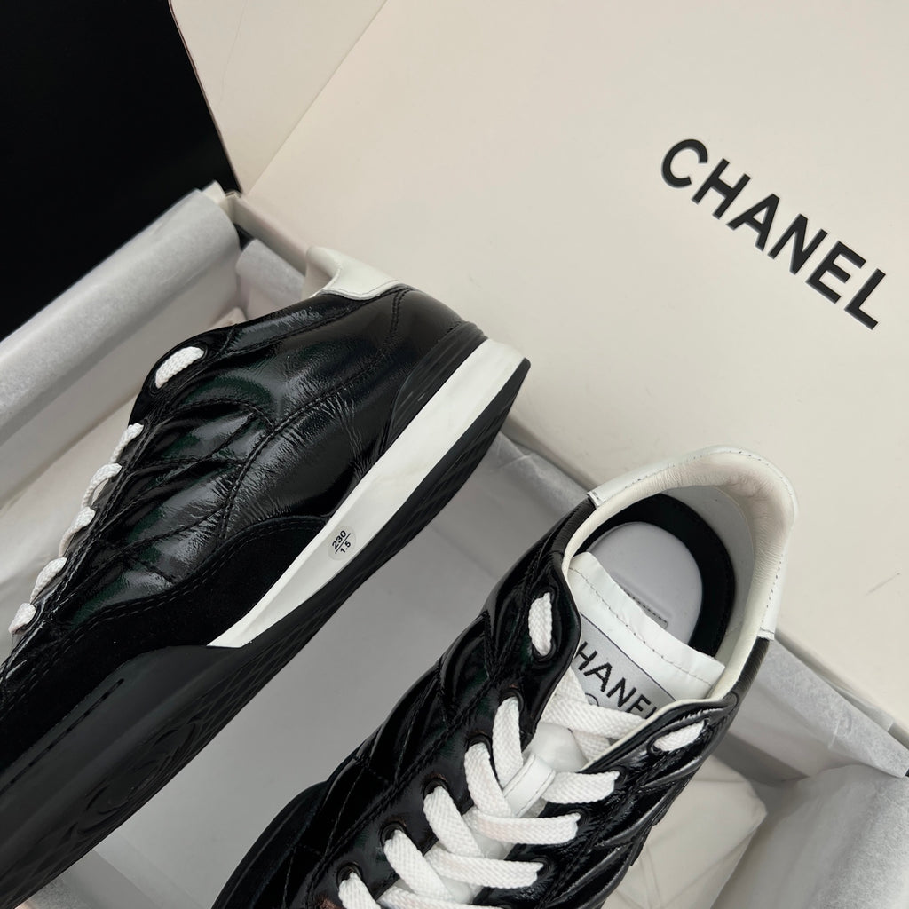 Black quilted unisex sneakers with white laces and side logo patch, low-top profile