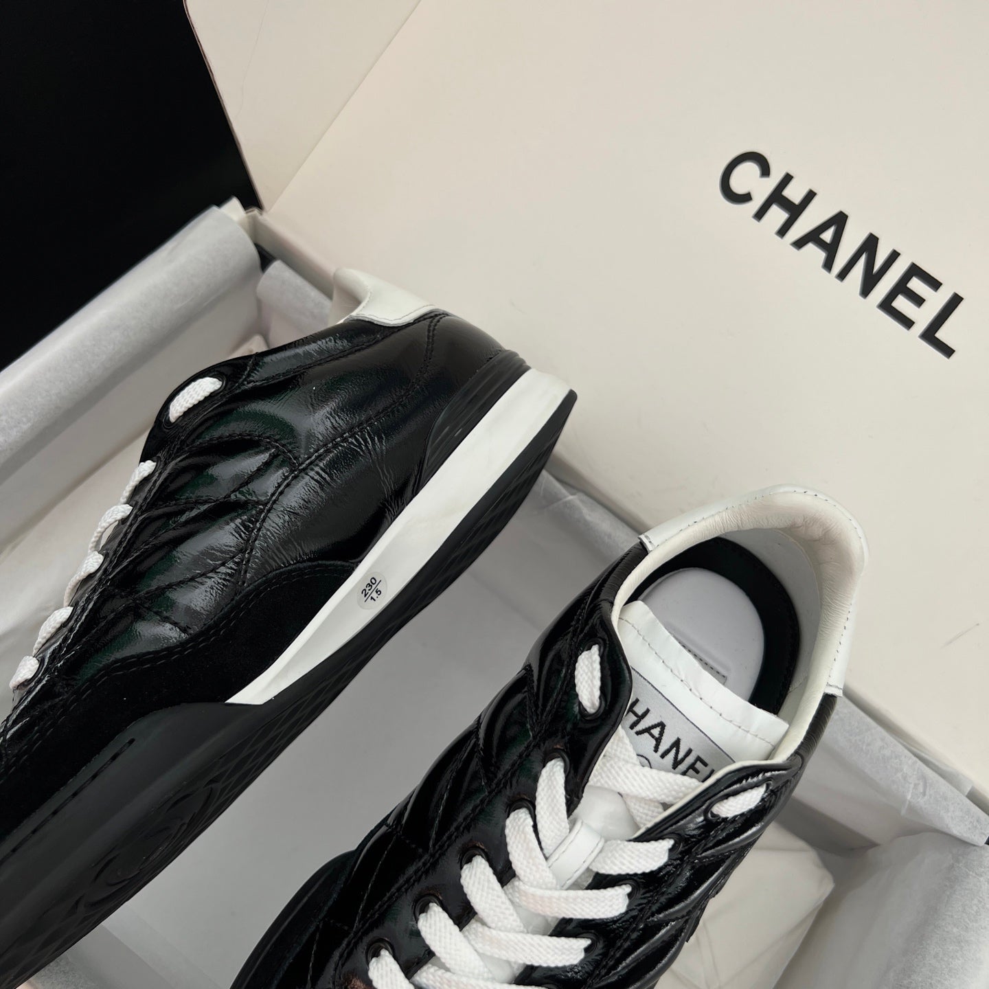 Black quilted unisex sneakers with white laces and side logo patch, low-top profile