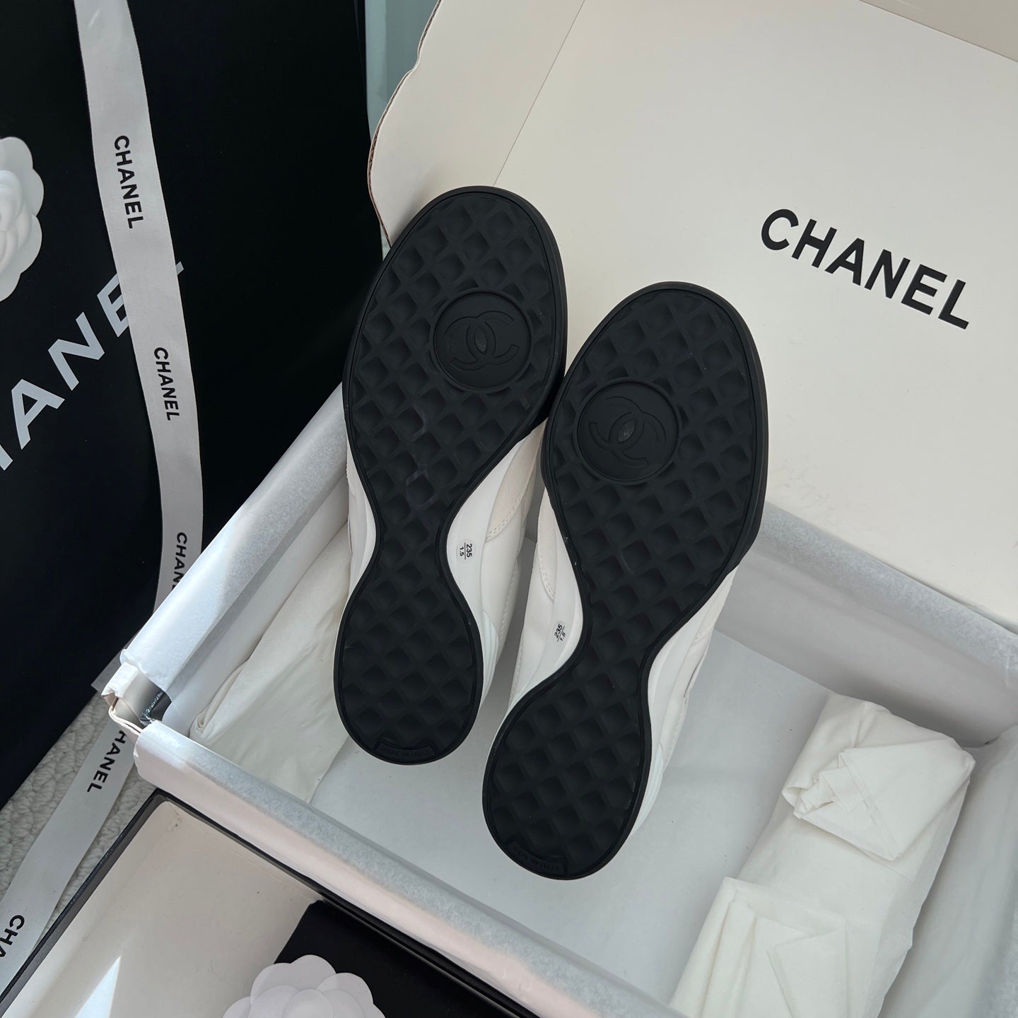 Chanel unisex sneakers, view of black textured rubber outsoles in the box