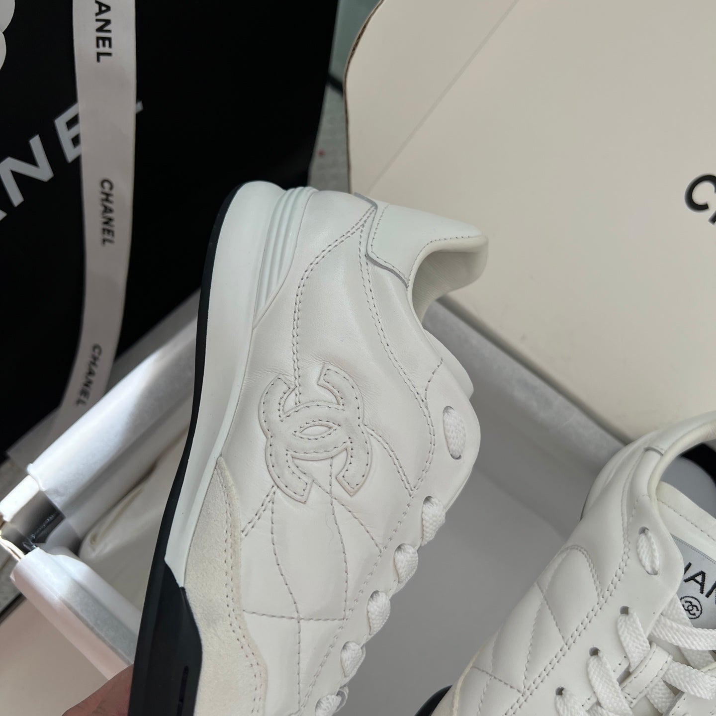 Chanel unisex sneakers, angled side view with white leather panel and stitched logo