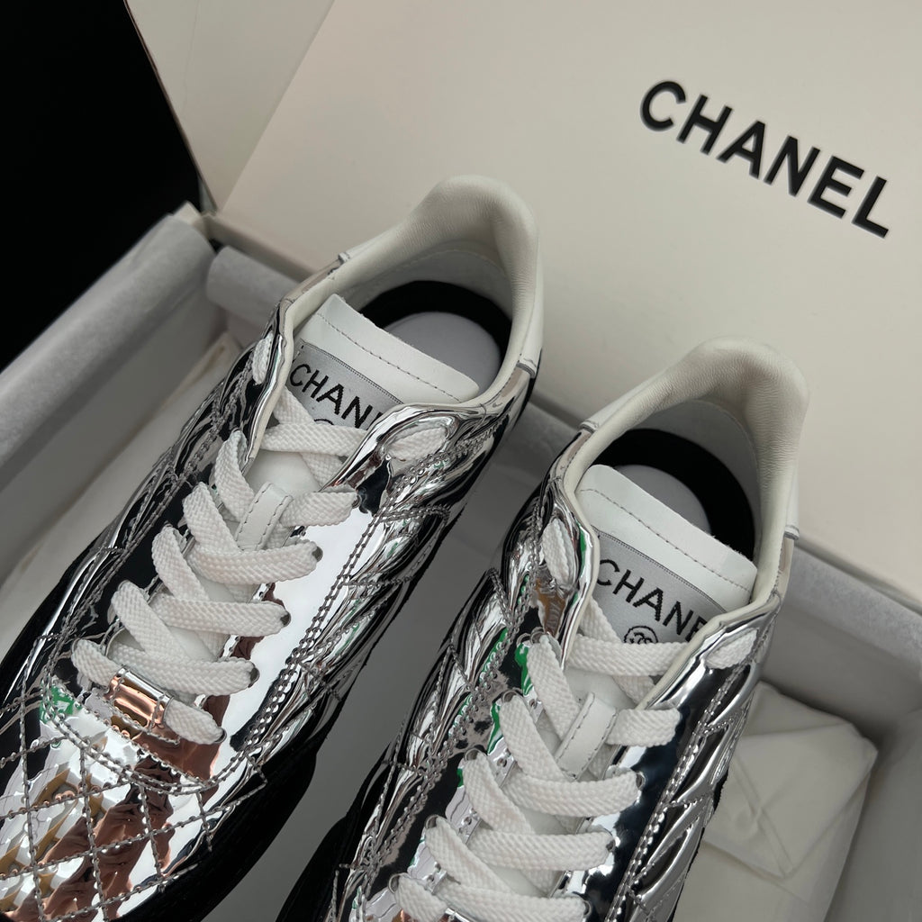 Metallic silver sneakers with white laces and green accent details