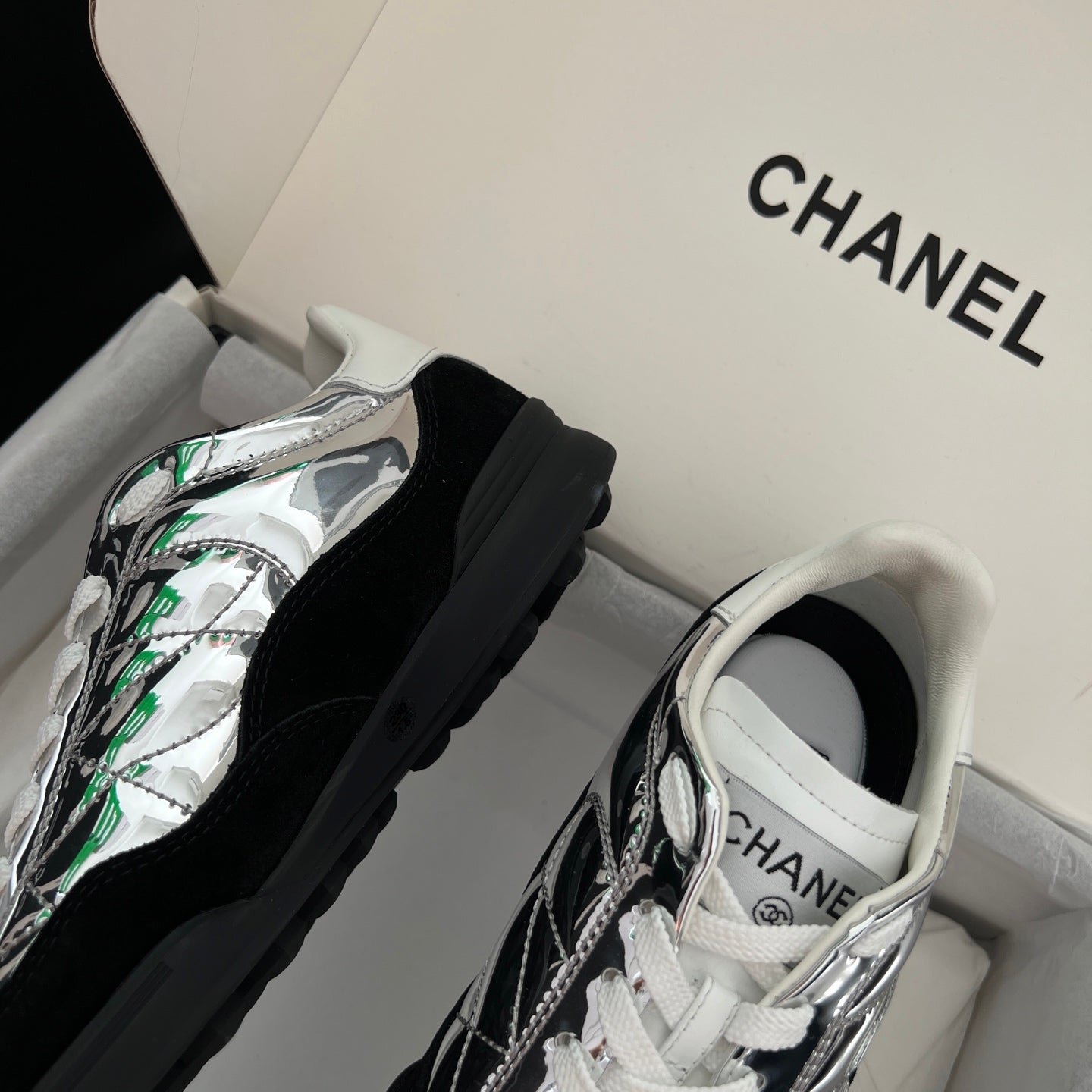Pair of low-top sneakers with metallic silver uppers, black panels, white laces