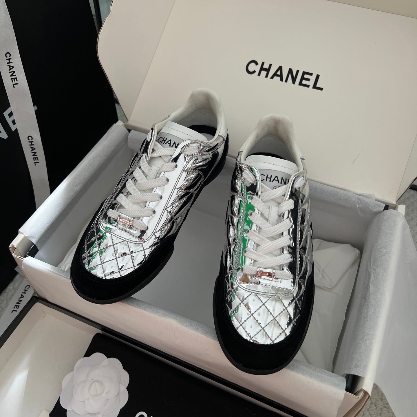 Metallic silver low-top sneakers with white laces and green trim