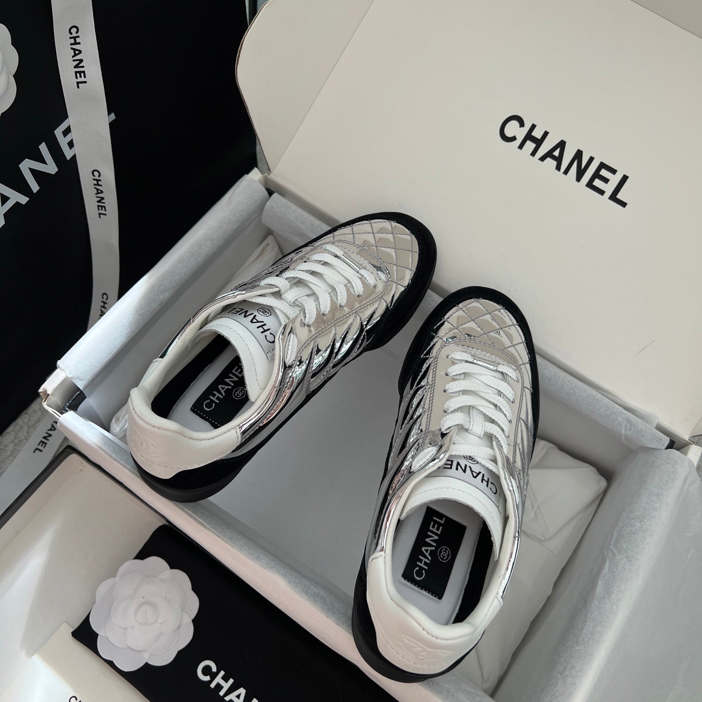 White and metallic silver sneakers with white laces in a shoebox